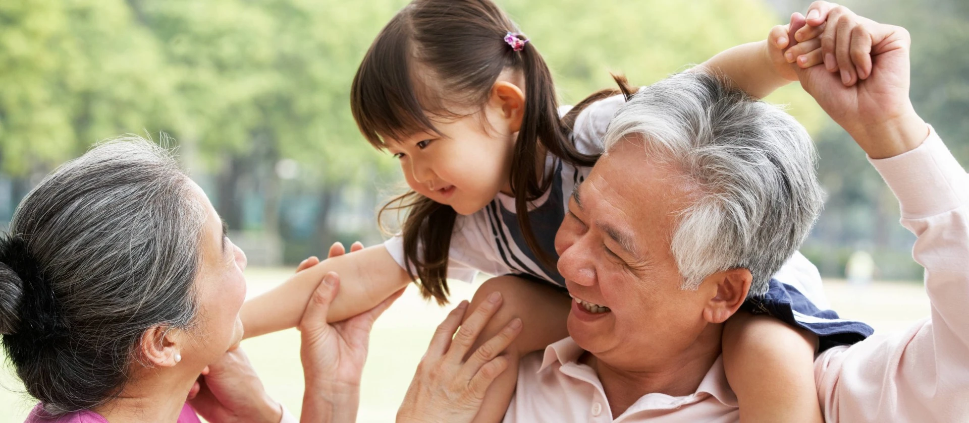 Chinese Grandparents Giving Granddaughter Ride On Shoulders